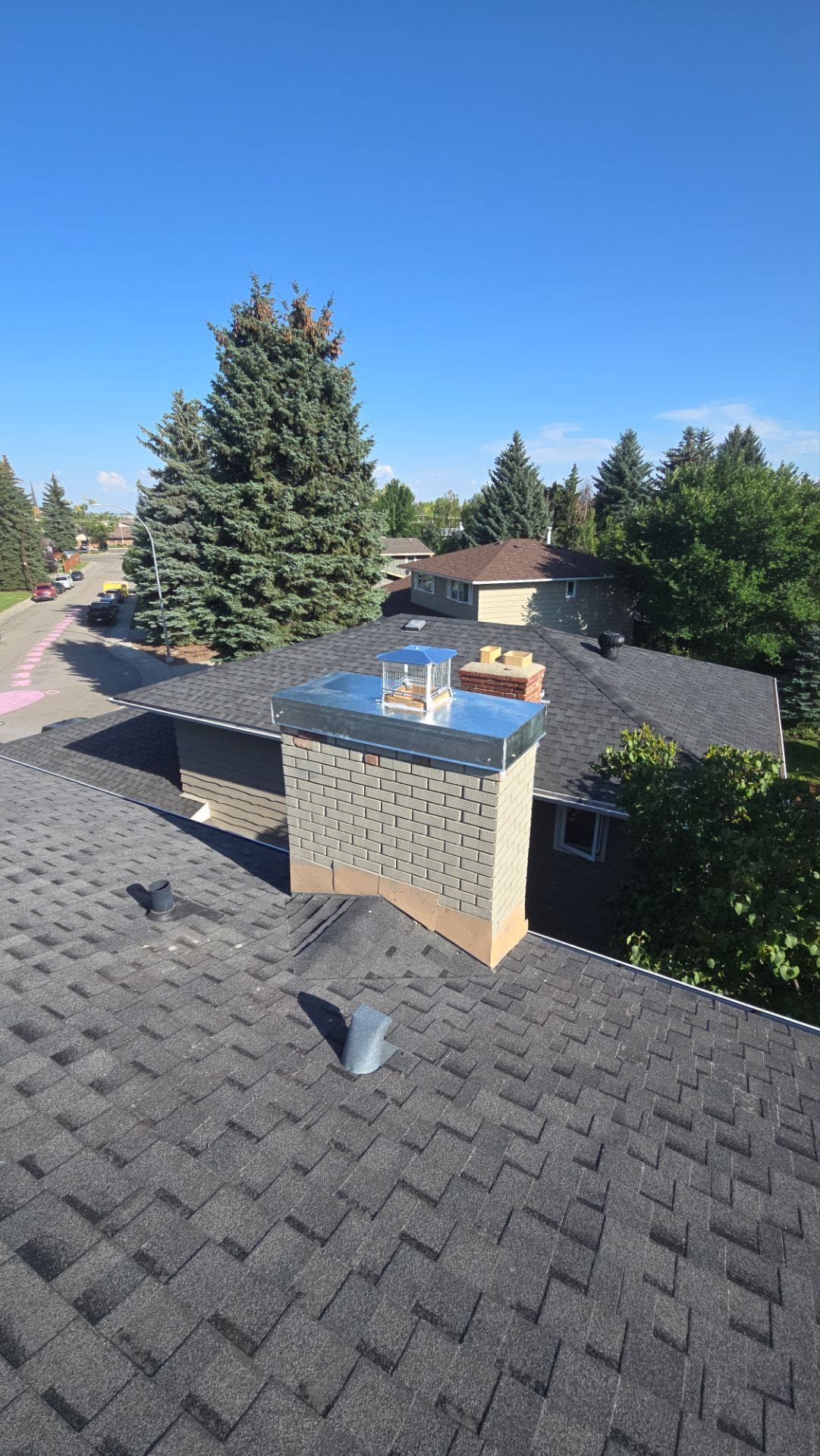 Finished custom galvanized chimney cap installation on a residential brick chimney in Calgary.